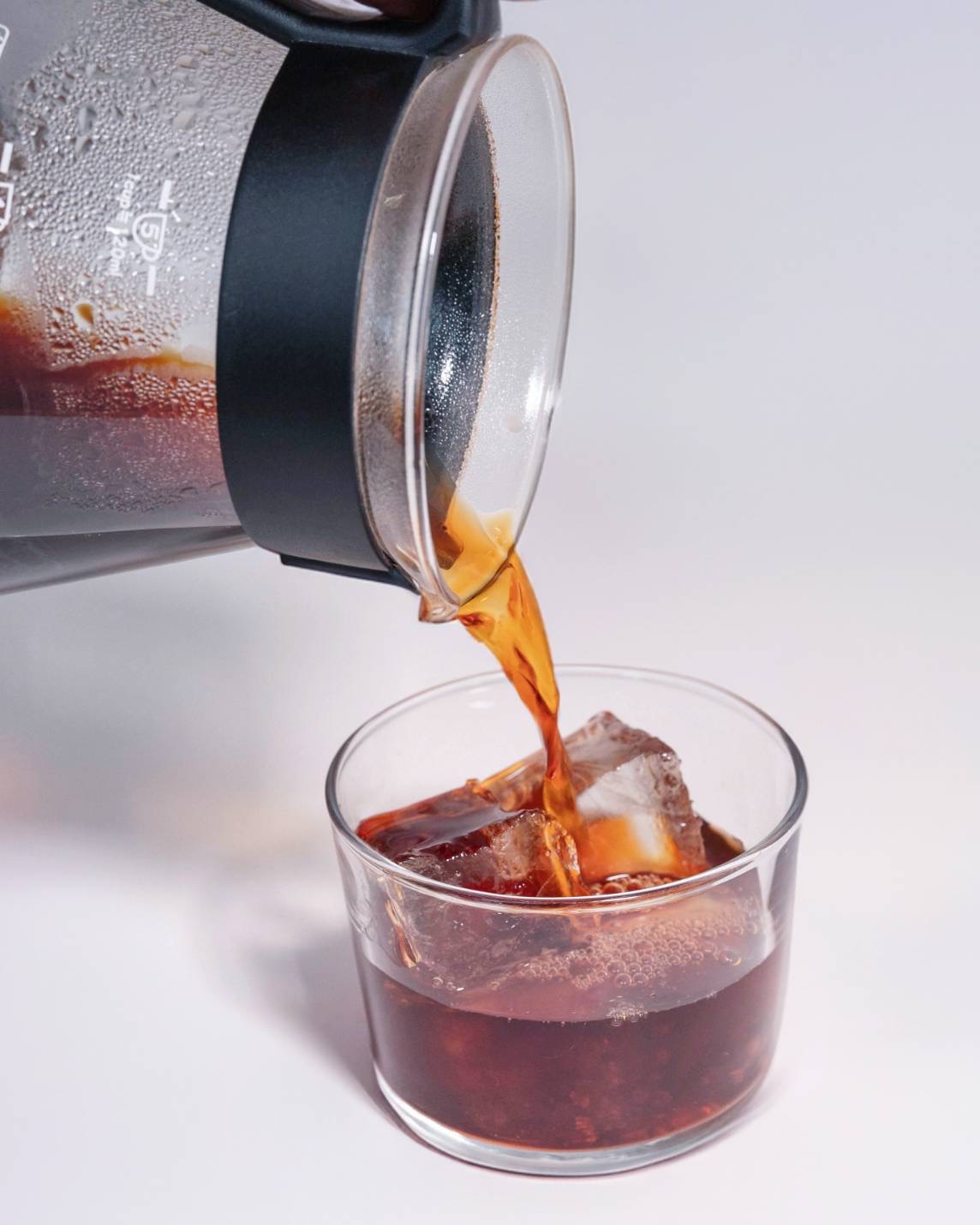 Cold brew pouring from a glass carafe over ice
